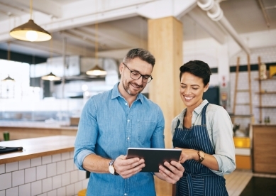 Male and Female Restaurant Owners Discussing Something on Tablet